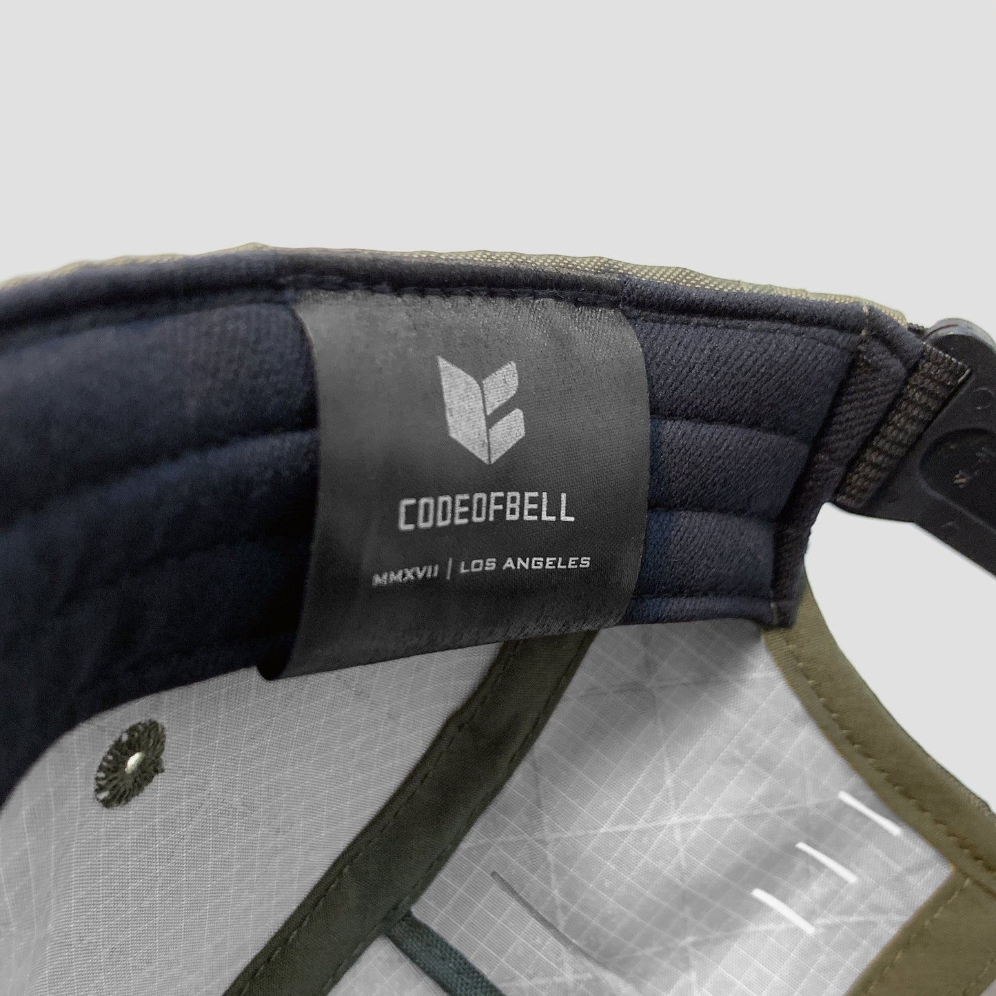 Utility hat made of durable waterproof coated ECOPAK™ fabric, with multiple laser-cut slits and ventilation openings, quick release adjustment strap, and reflexive tab for night time visibility.